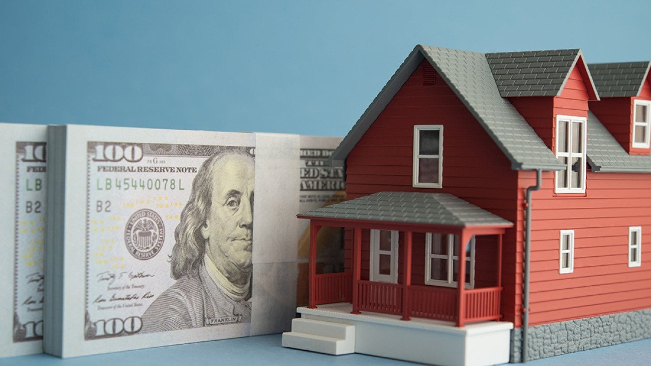 US dollar banknotes and a figure of a home.