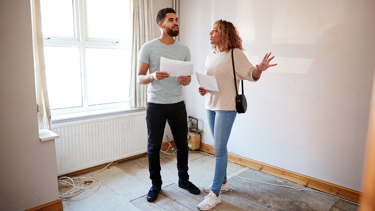 A couple surveys a house's area for renovation.