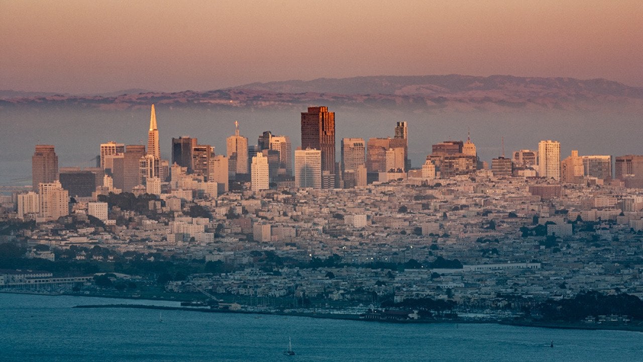 A foggy view of the San Francisco skyline during sunset.