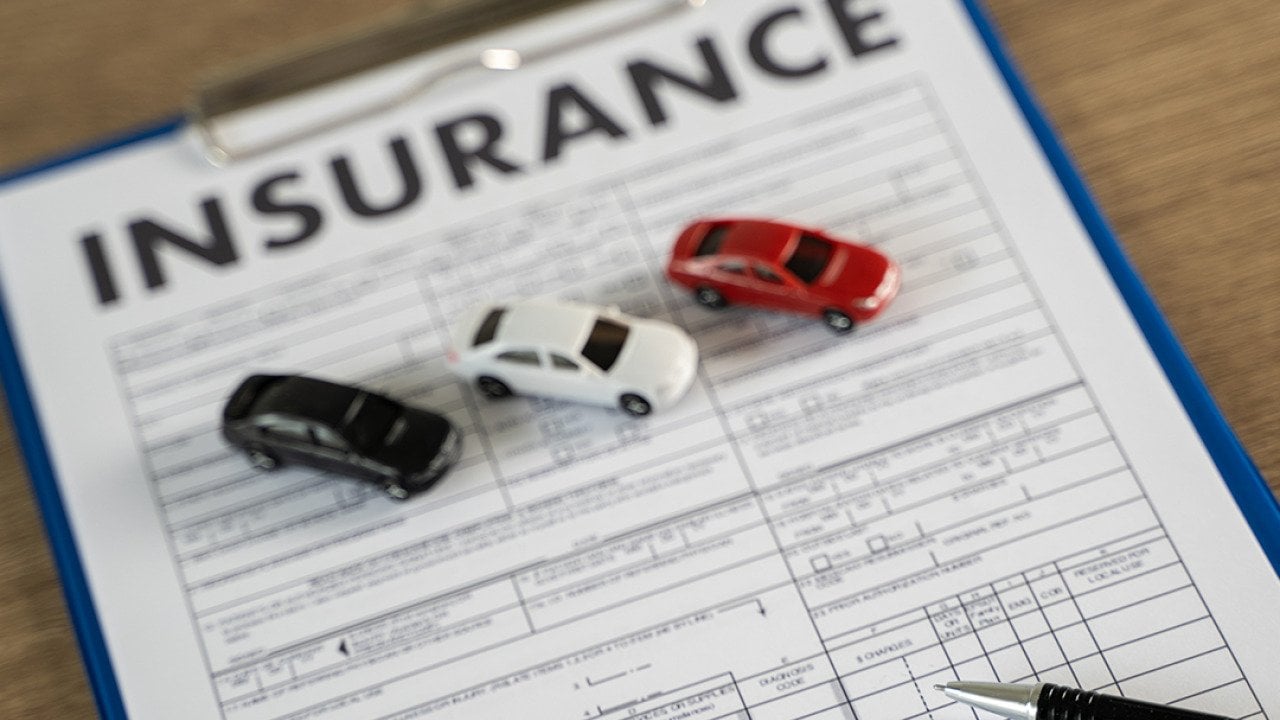 Three small figures of cars on top of a car insurance document.
