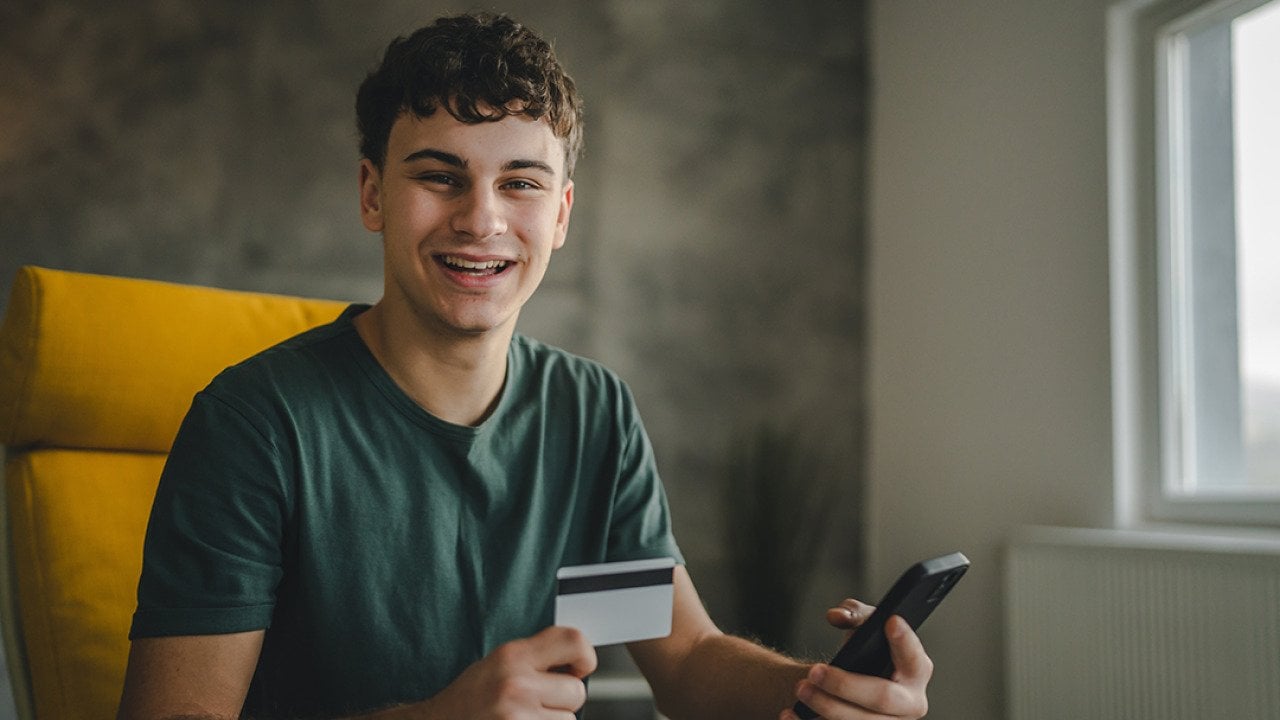 A happy young man using a credit card to purchase online.