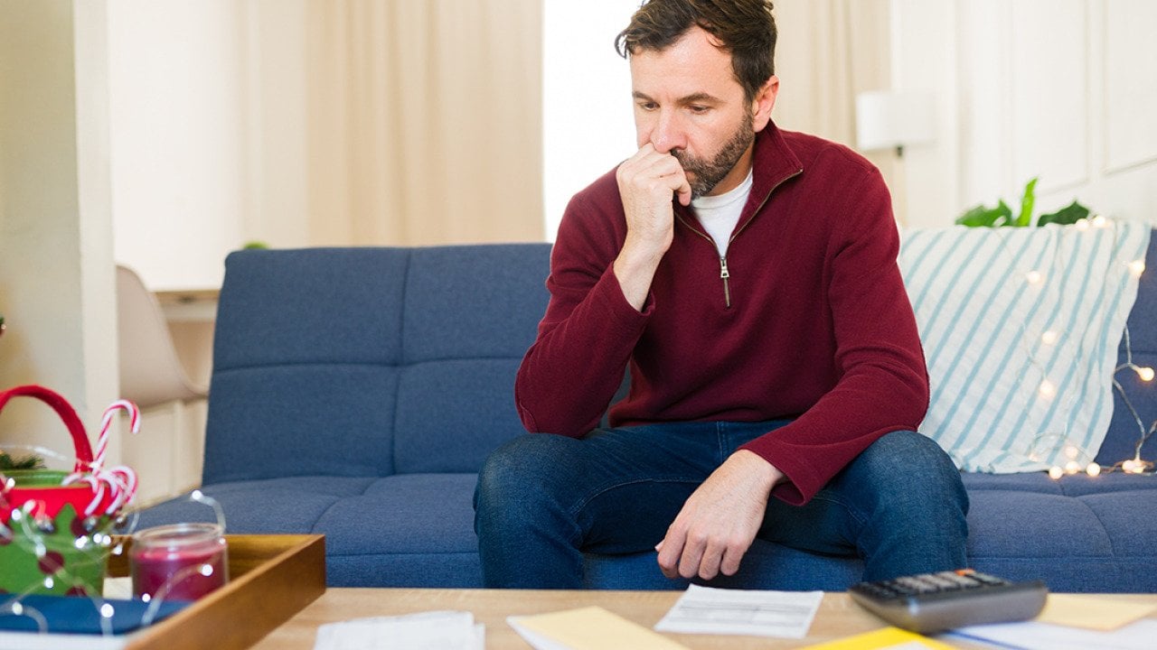 A worried man calculating expenses at home.