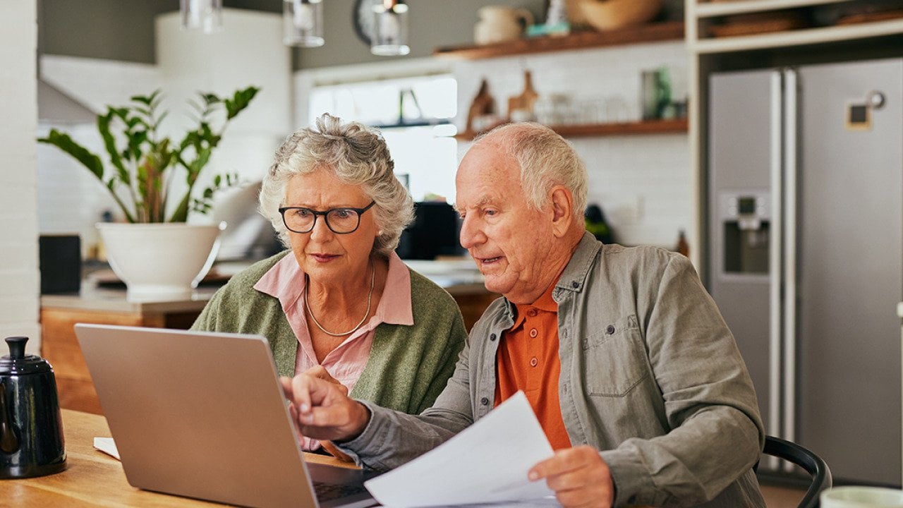 A senior couple using a laptop to review documents.