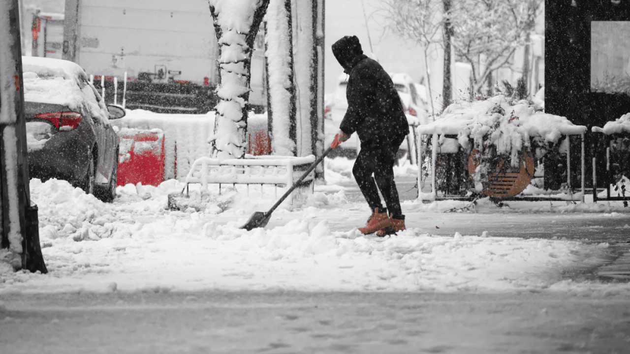 A person shovels snow in a neighborhood.