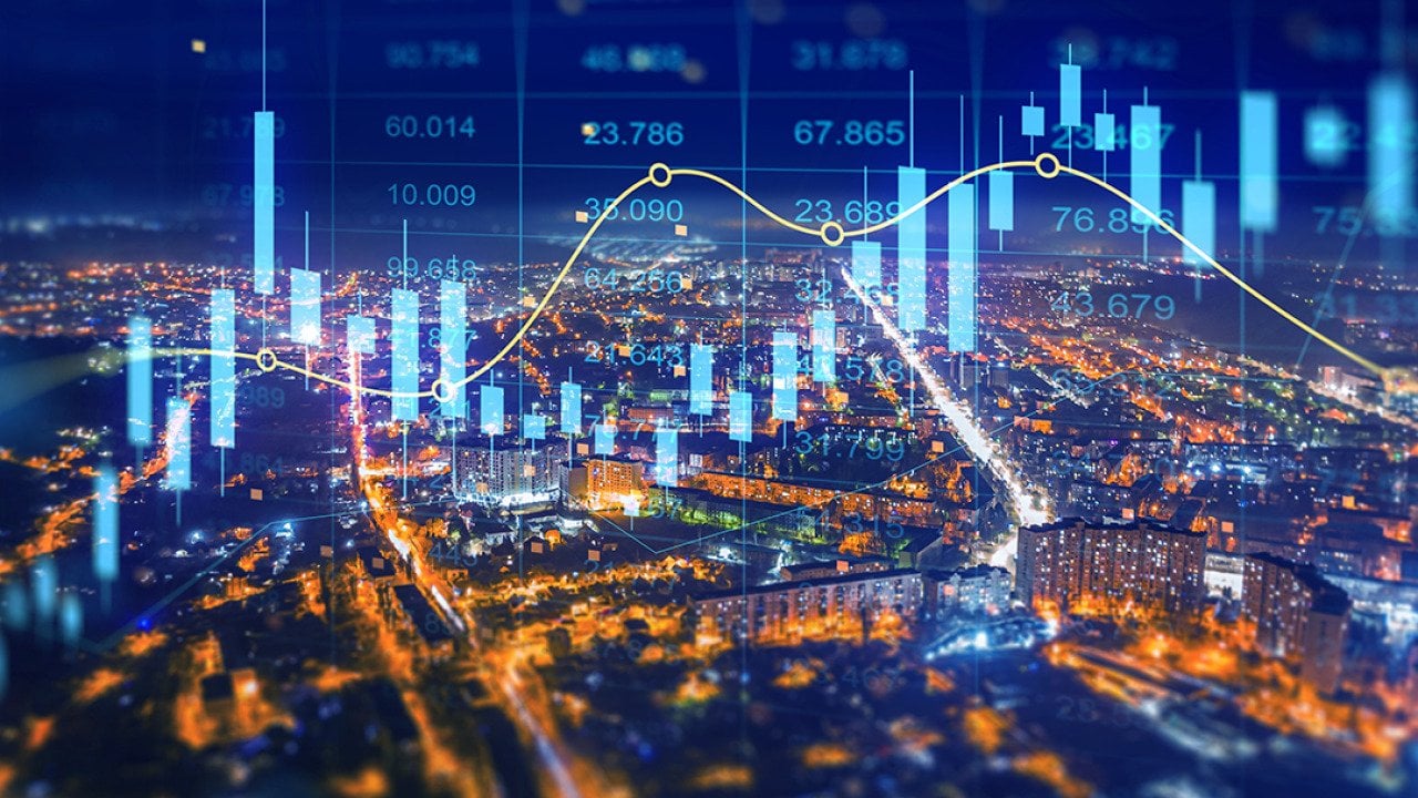 Aerial view of a city at night illustrated with holographic finance charts.