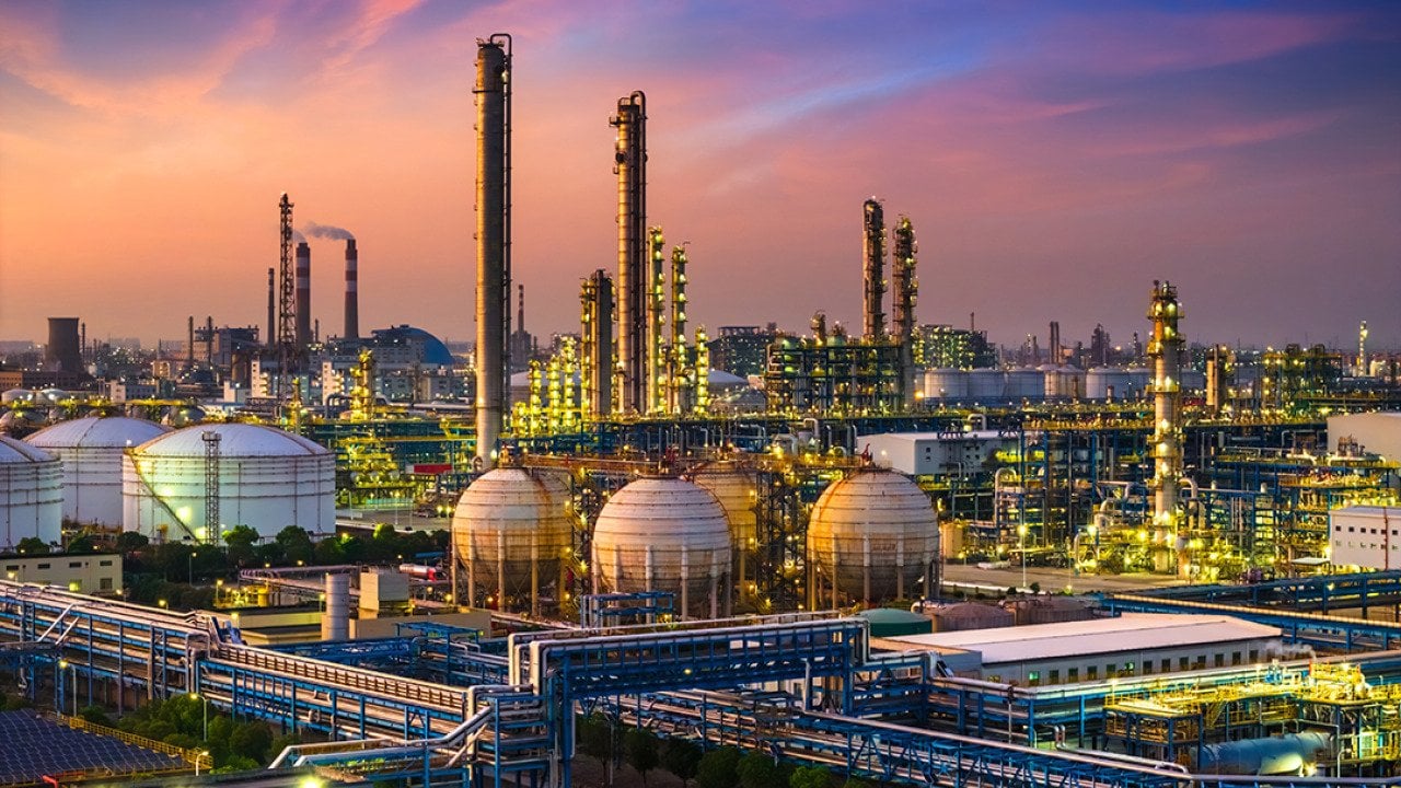 A view of a large industrial oil refinery and chemical plant during sunset.