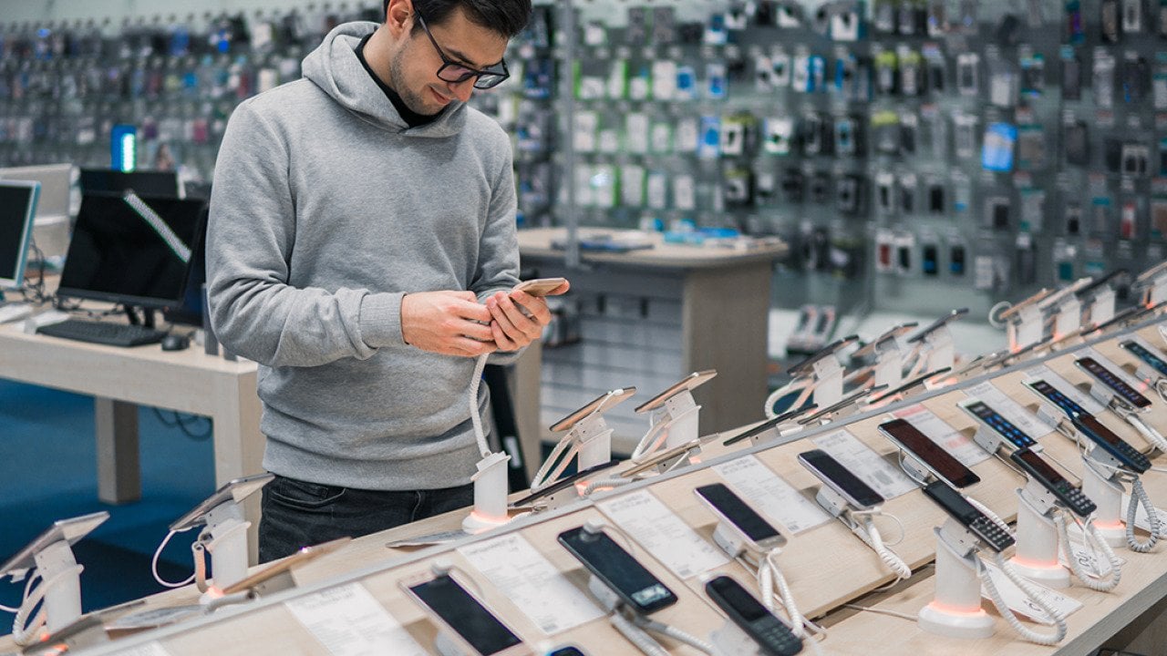 Man checking phone models at a store.