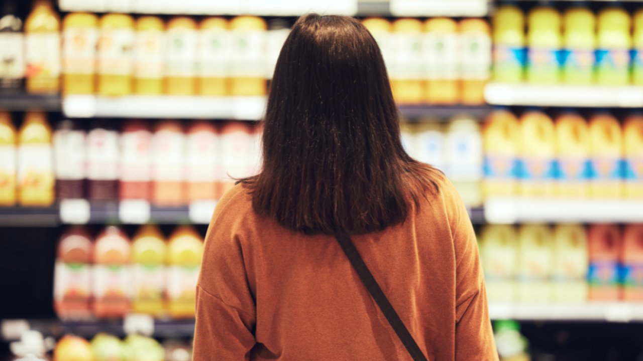 A person looking at shelves of juice at a grocery store.