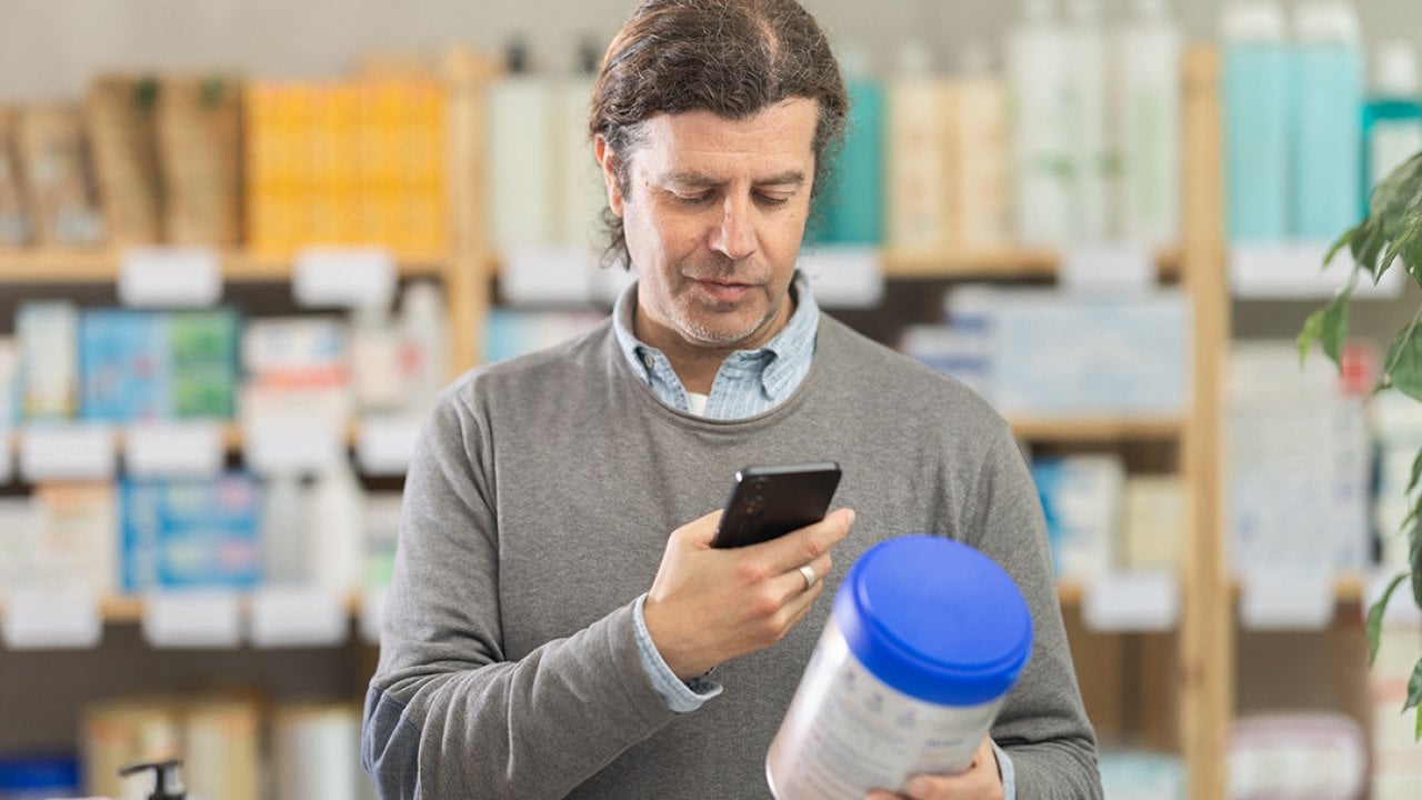 A man scanning a baby food's information while shopping.