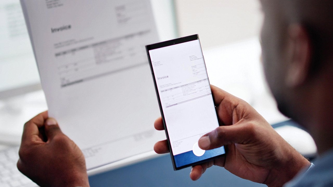 A man taking a photo of an invoice document using a phone.