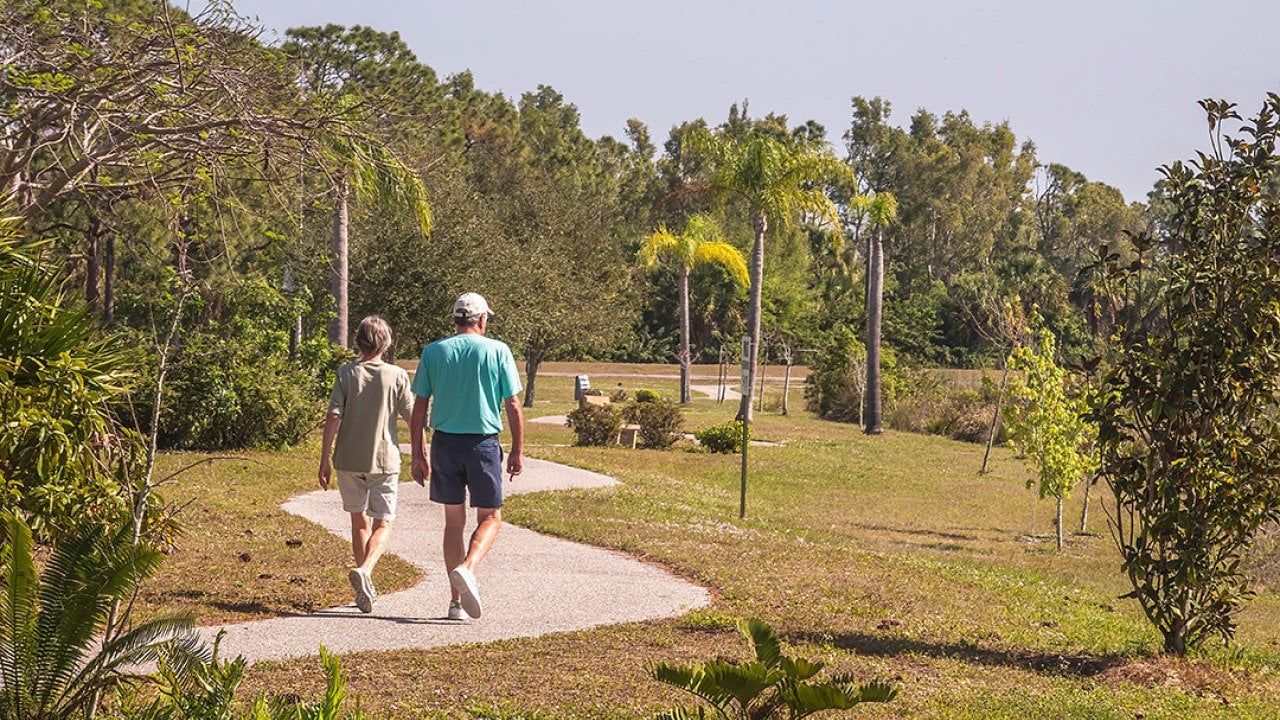Two seniors walking a trail at a park during spring time.