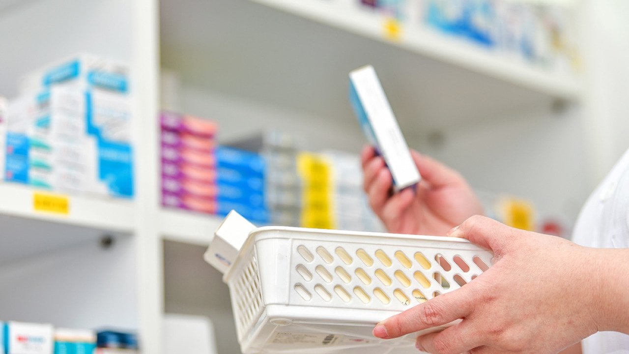 A pharmacist holding a basket to fill out a prescription.