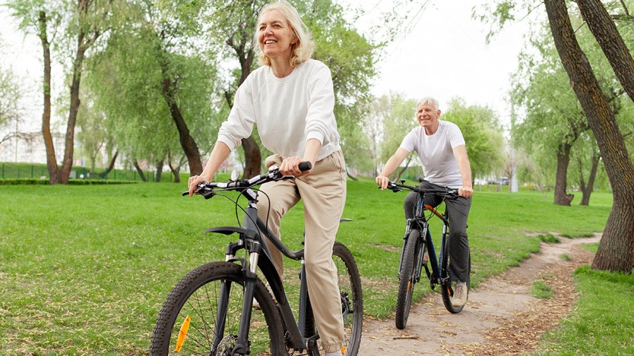 A senior couple riding bikes in a park.