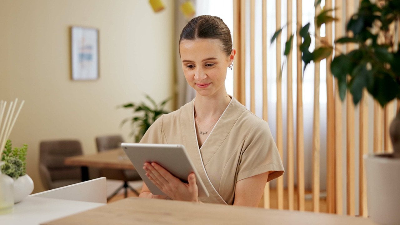 A female front desk staff at a spa using a digital tablet to look at schedule.