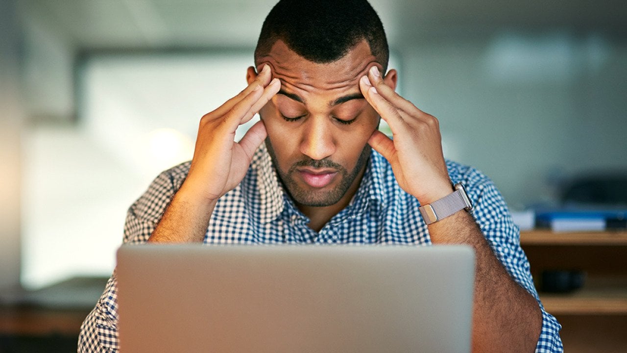 A stressed businessman facing a laptop.