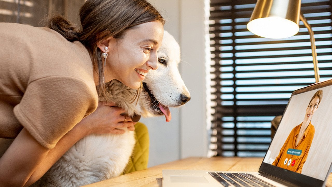 A young woman sharing a video call with her dog at home.