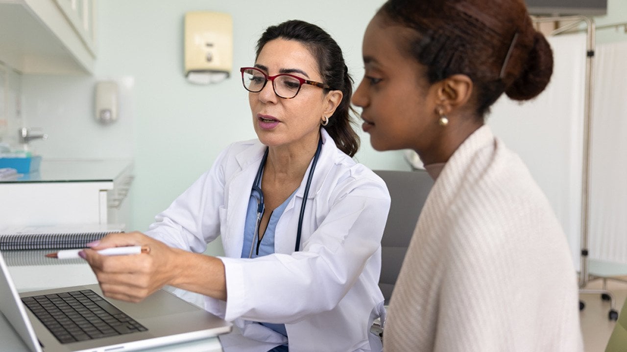 A young black woman going over medical examination results with her female doctor.