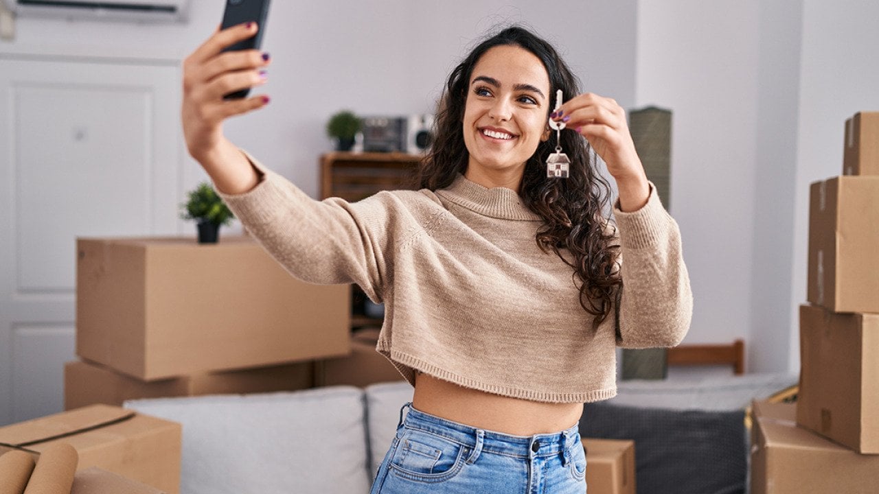 A young woman taking a selfie with her new home's keys.
