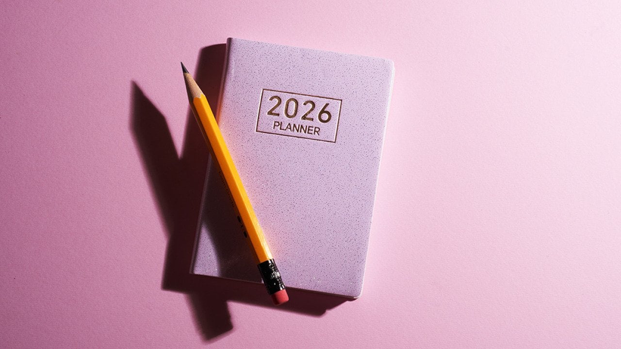 A pink 2026 planner with a pencil against a pink background.