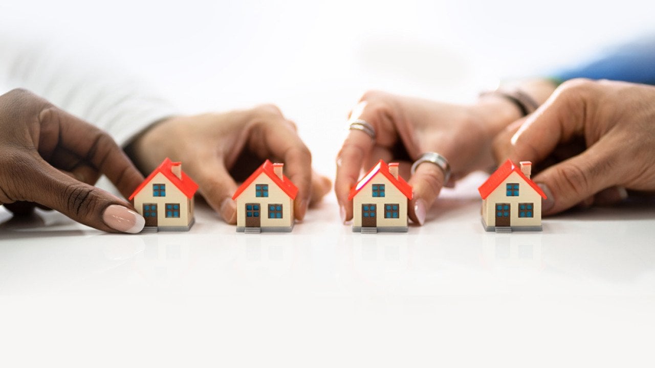 People's hand holding tiny models of houses.
