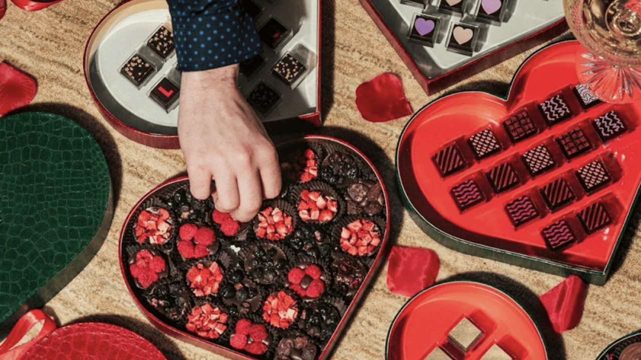 Person picking from a heart-shaped box of chocolates.