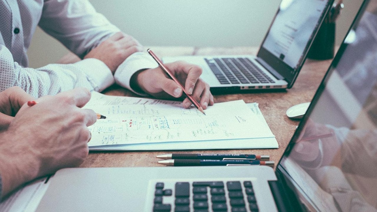 Businesspeople planning on paper in front of their laptop.s