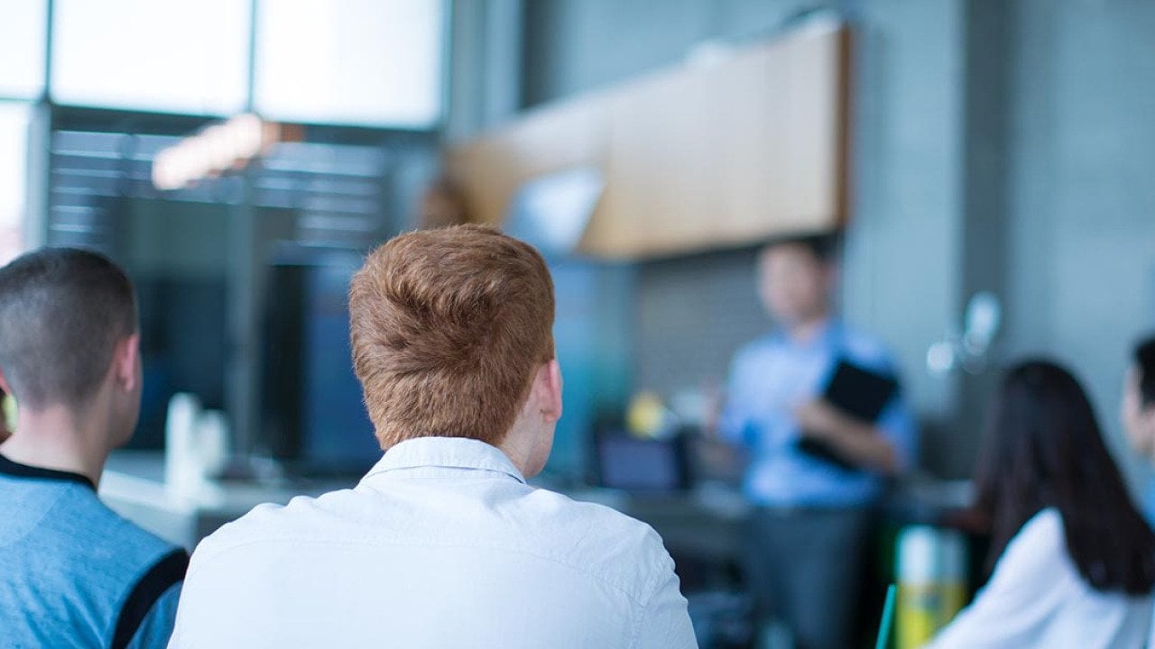 A sales team listening to a presenter in the office.
