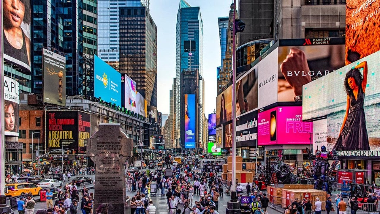 Crowds of people and lit up billboards around Times Square in New York City. 
