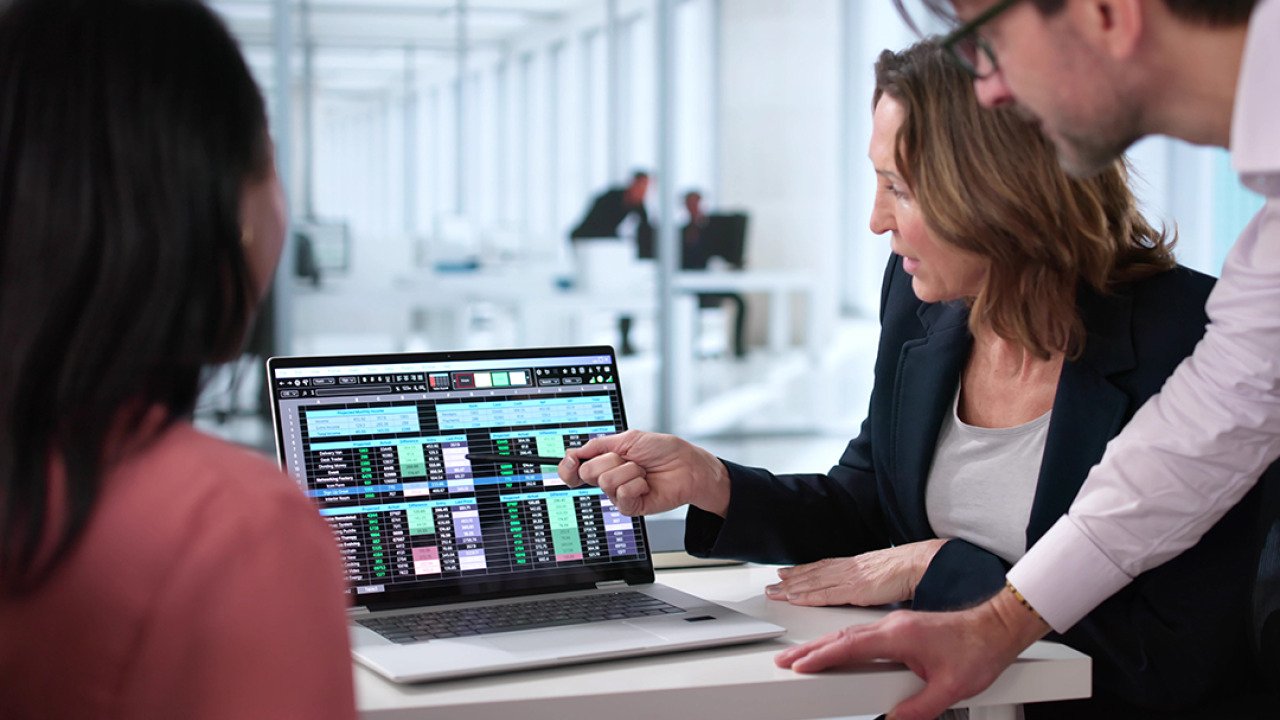 A business team reviewing billing reports displayed from a laptop.