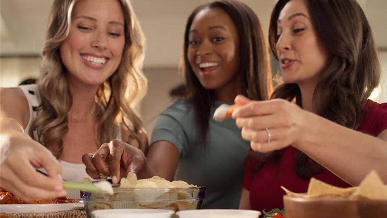 A group of women eating chips with french onion dip.