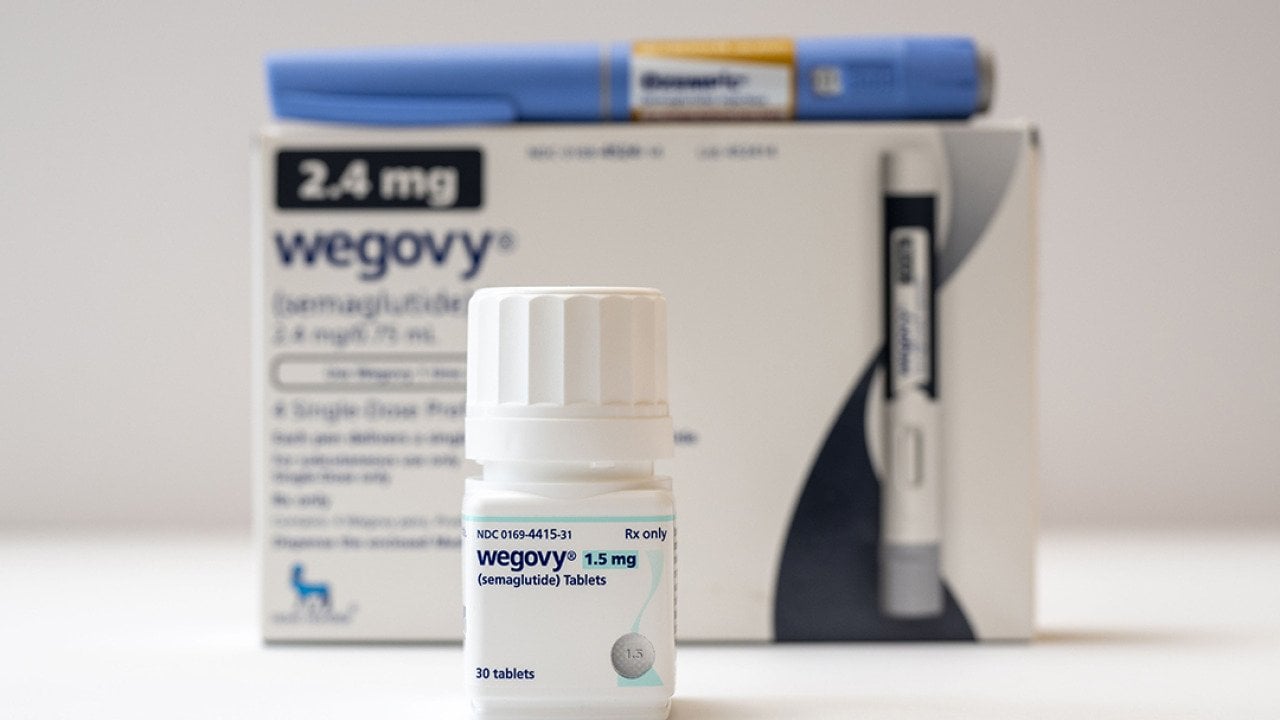 A bottle of Wegovy tablets its box and an Ozempic pen in the background.
