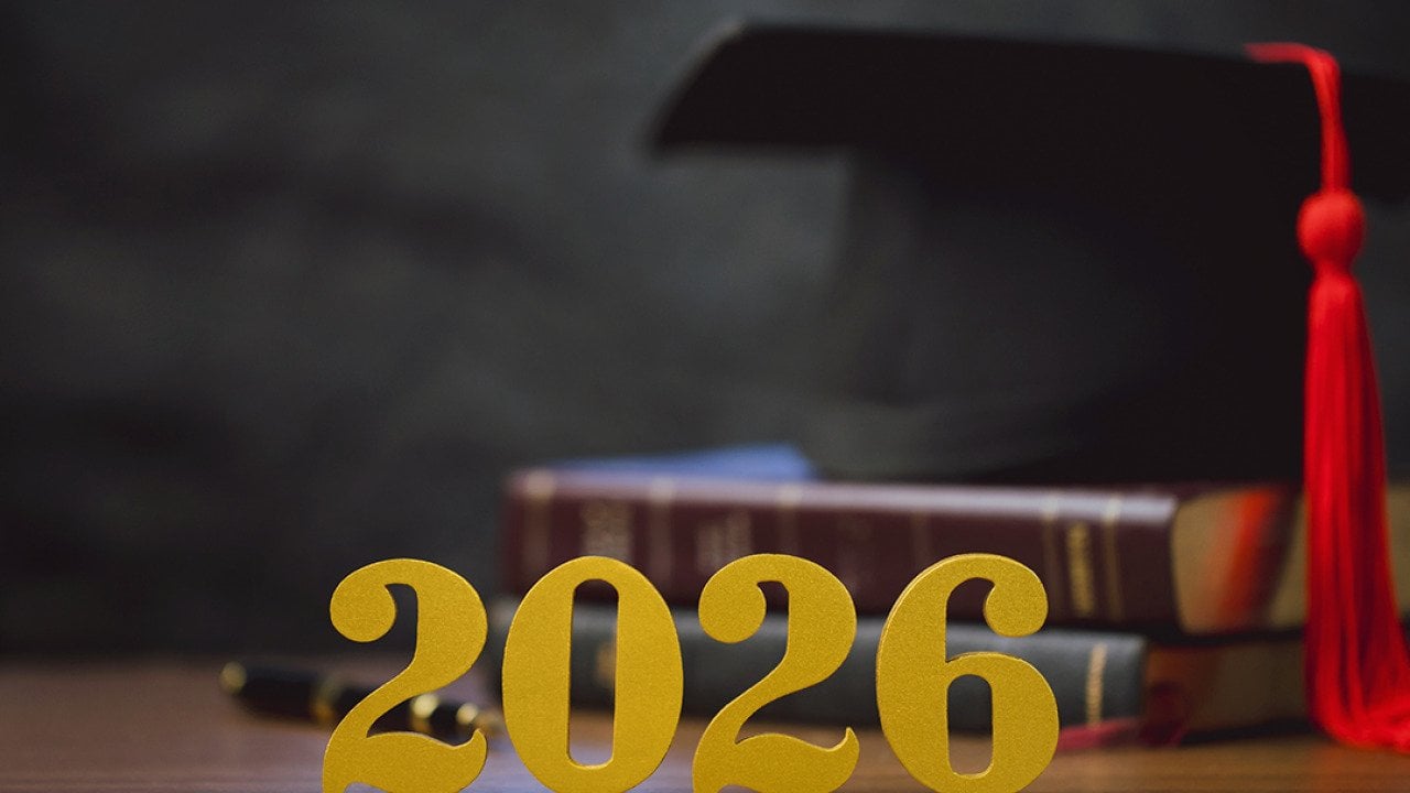 Golden '2026' numbers in front of a stack of books and a graduation cap.