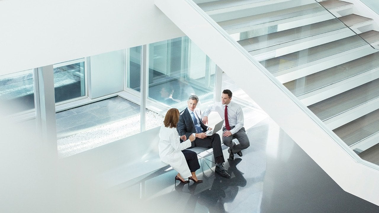 A doctor and administrators talking in a hospital lobby.