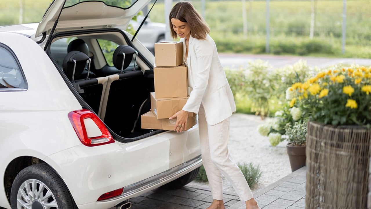 A businesswoman picking up parcels from the trunk of her car.