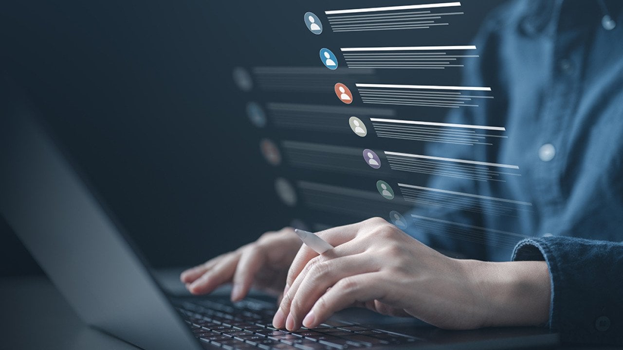 Person typing on a laptop illustrated with a list of contacts software graphics.