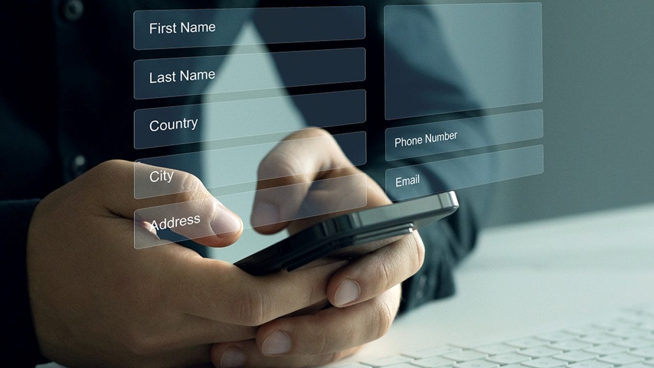 Person typing on smartphone illustrated with personal data sheet graphics.
