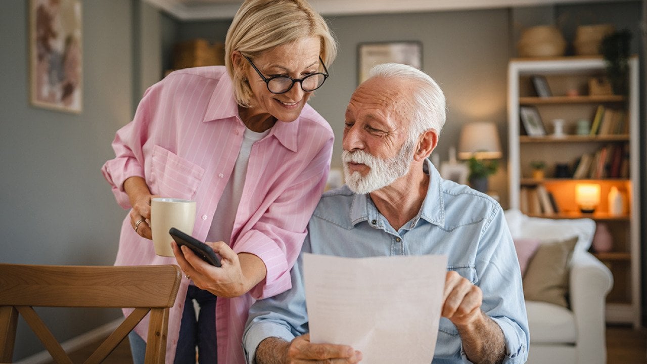 A senior couple reading a document and checking information online together.