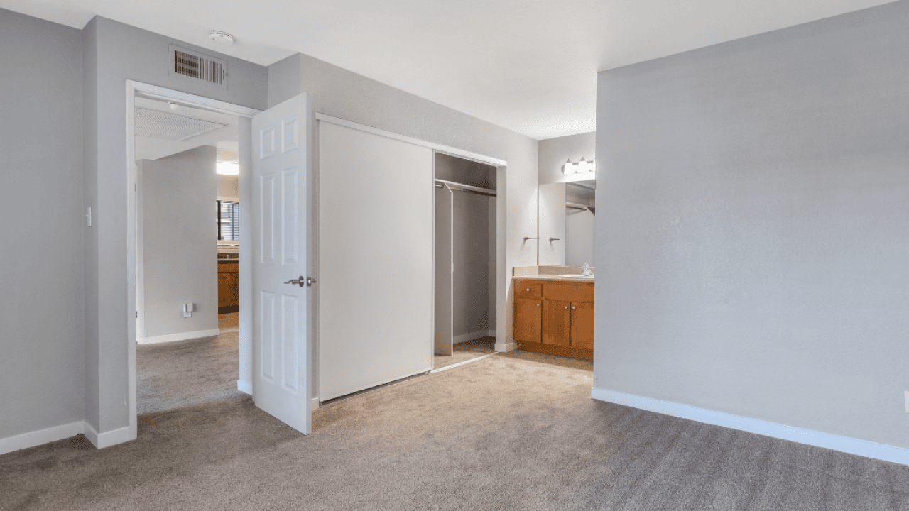 Interior views of an unfurnished apartment unit featuring carpeted bedrooms, built-in vanities, and a gray wall color.