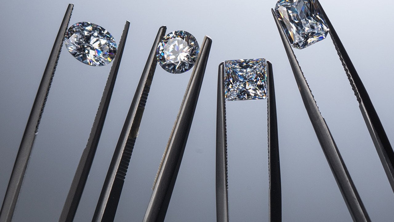 Close up of lab grown diamonds held by tweezers.