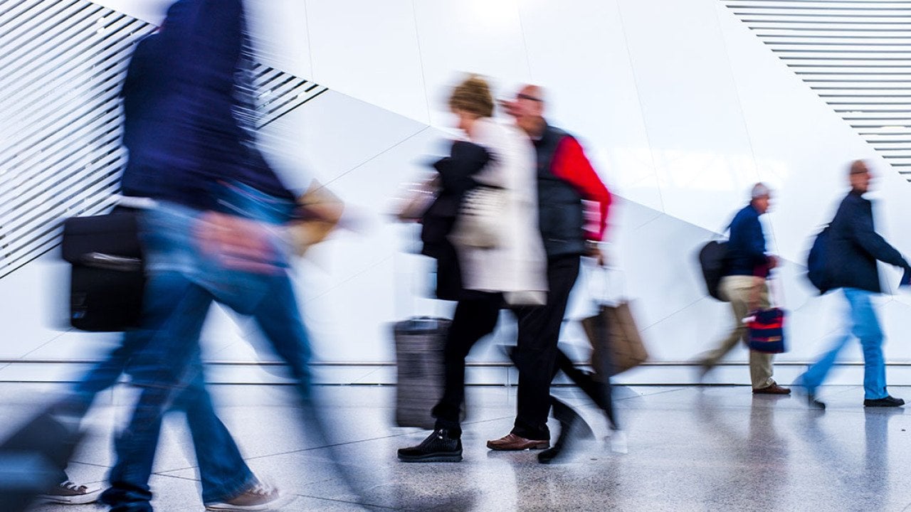 A motion blur shot of passengers walking inside an airport.