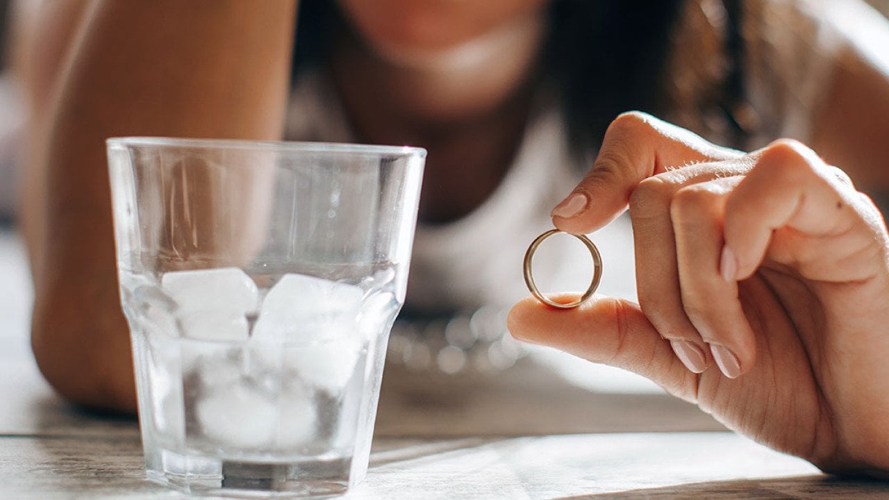 A sad woman holding wedding ring.