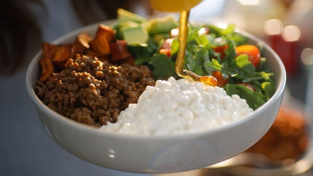 Honey poured onto a bowl of chili, cottage cheese, and salad dish for a protein-rich source meal.