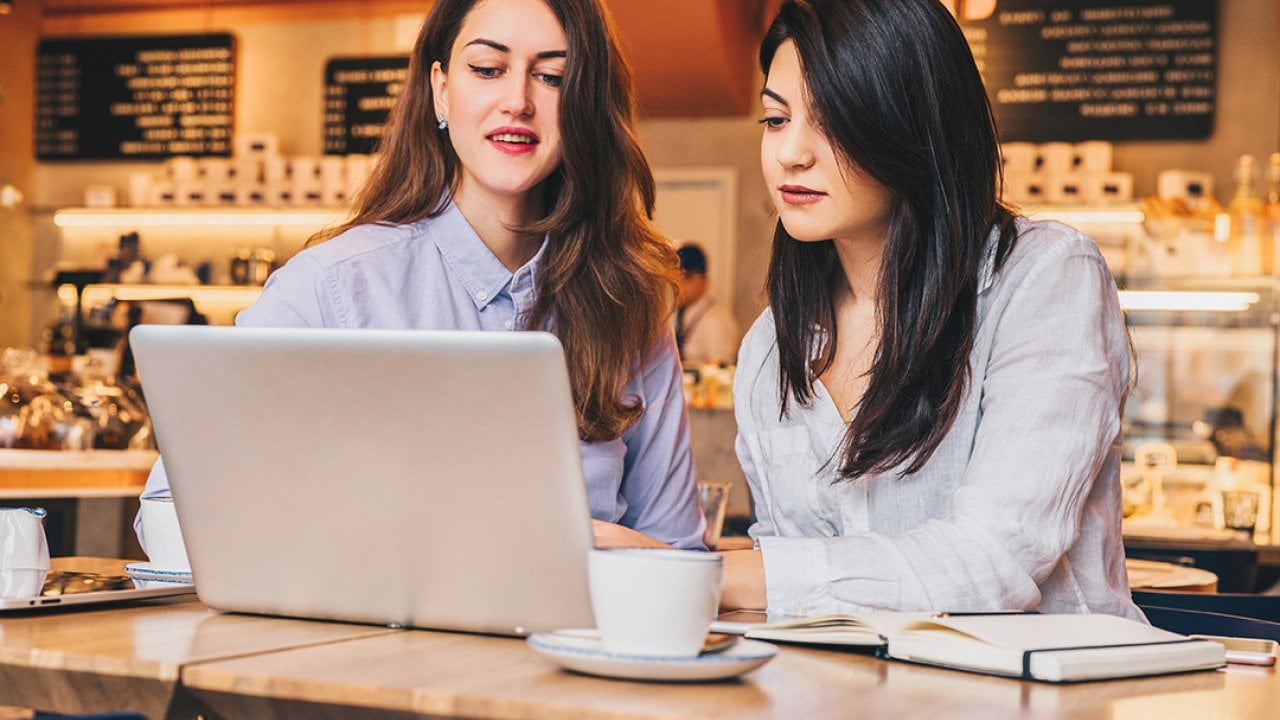 Two businesswomen at a cafe working on a project together.