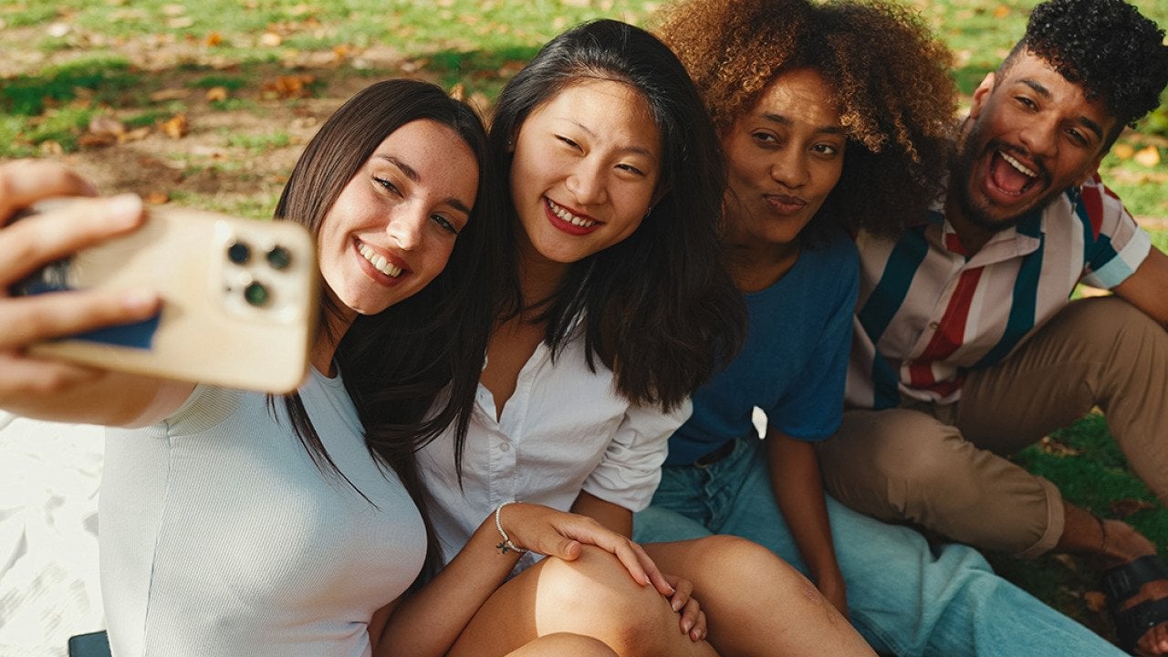 A group of four friends taking a selfie together outdoors.