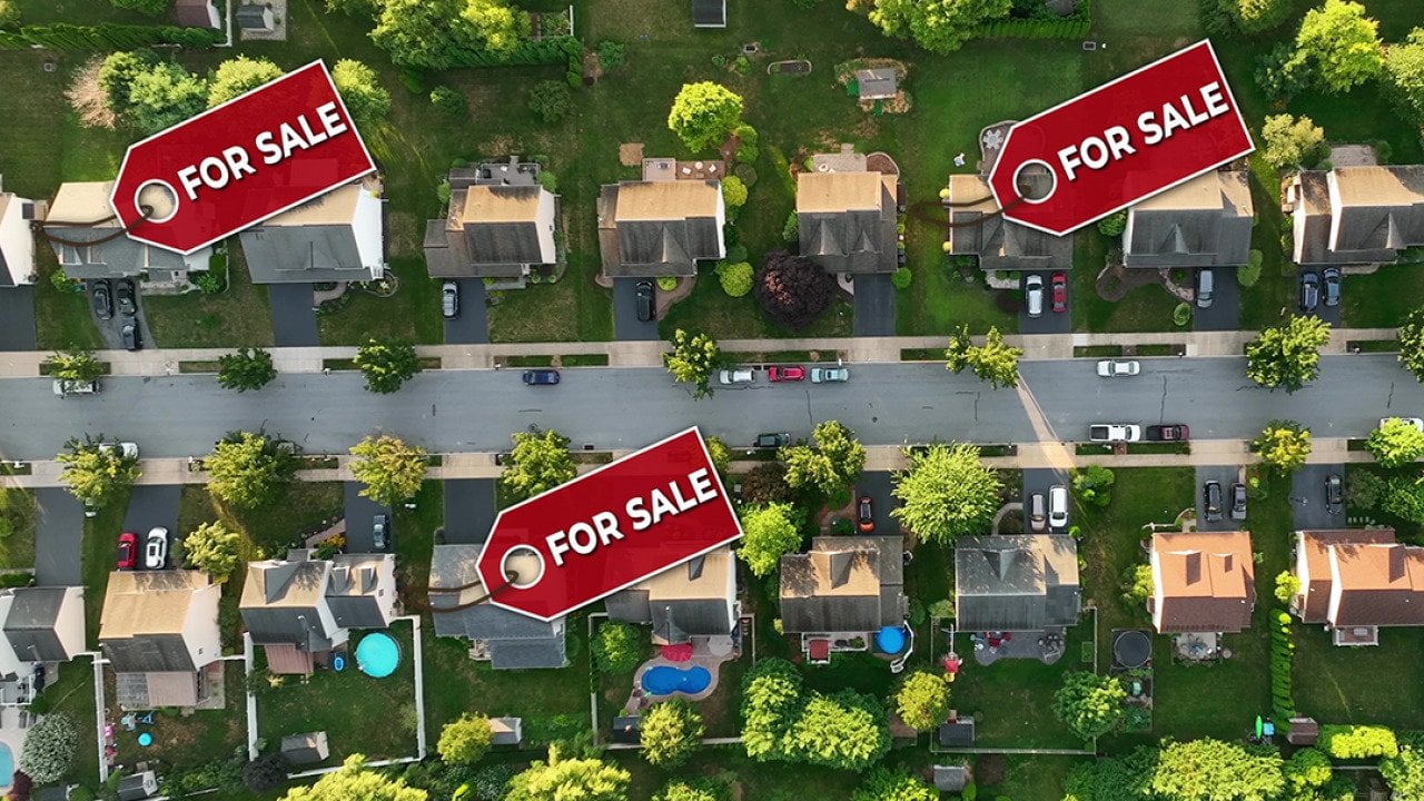A top aerial view of a neighborhood with some homes marked ‘For Sale.’
