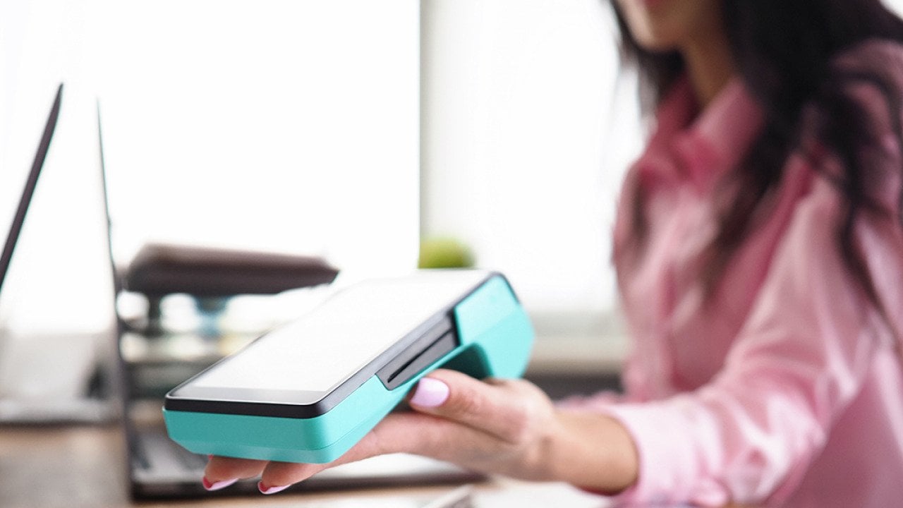 A person holding a banking mobile device in a workplace. 
