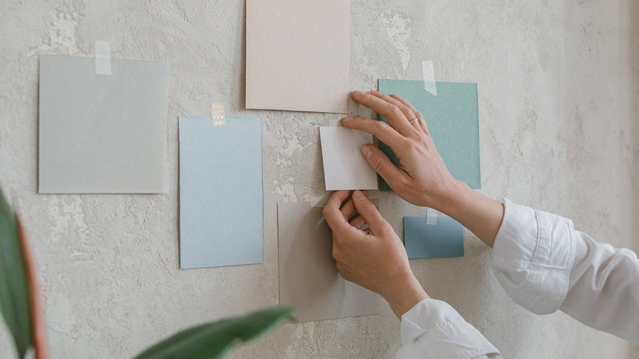 Woman hanging paint color mock ups on a wall.