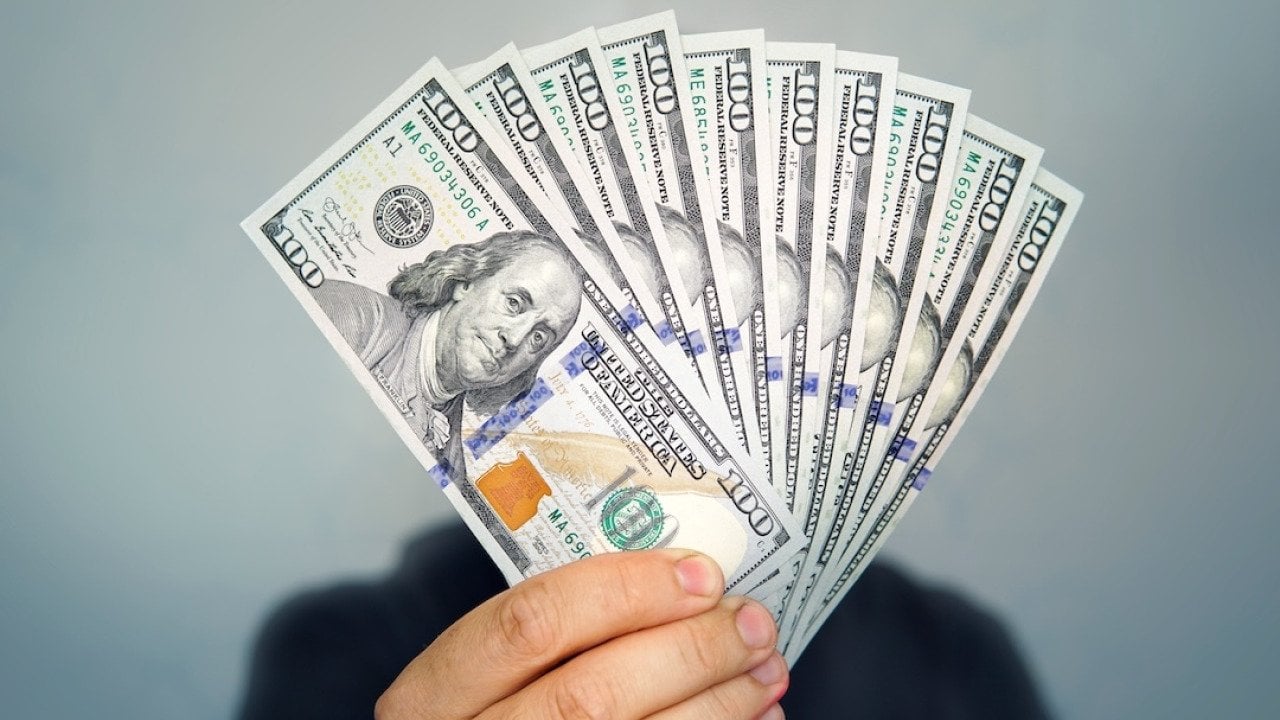 A focused shot of a hand holding dollar bills.