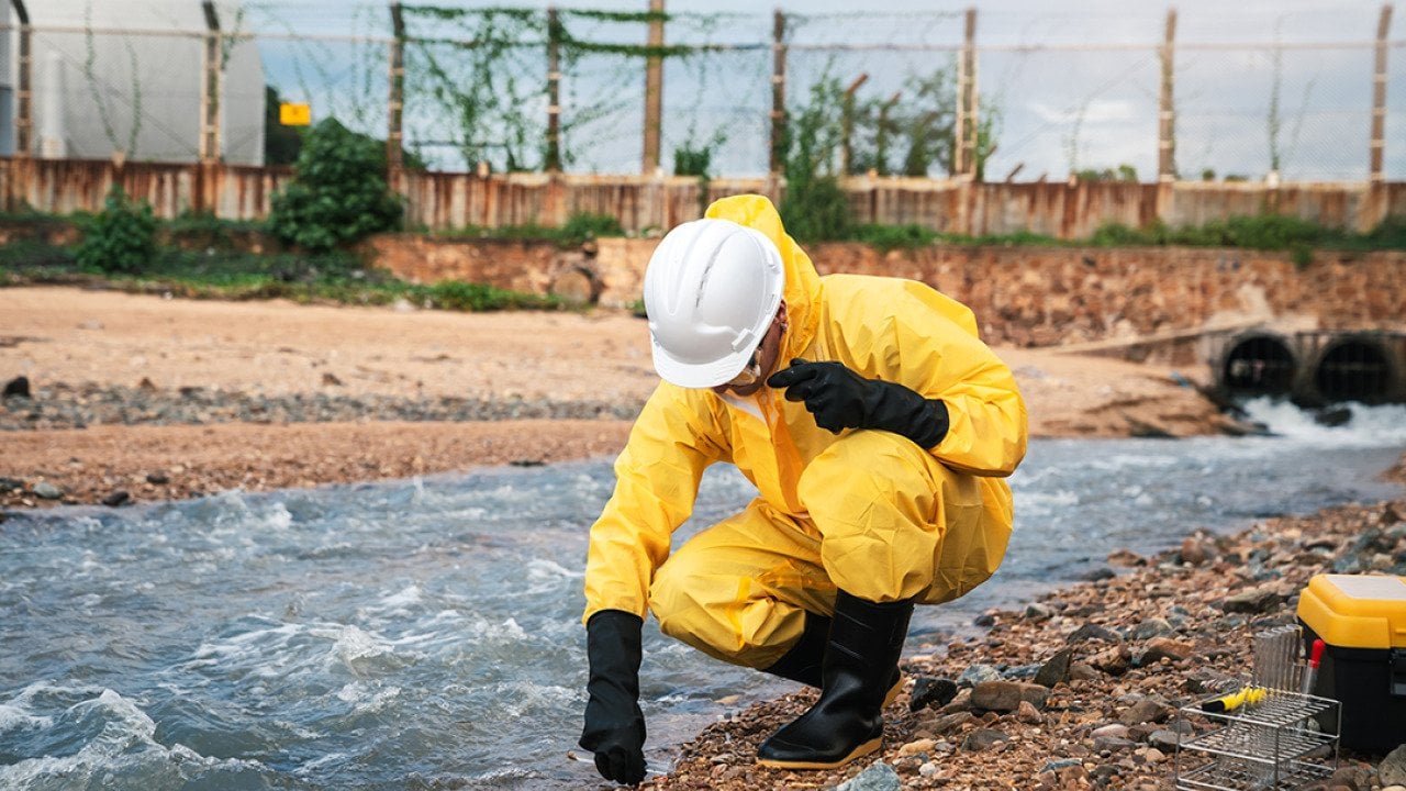 A factory worker in hazmat suit performs environmental inspection.