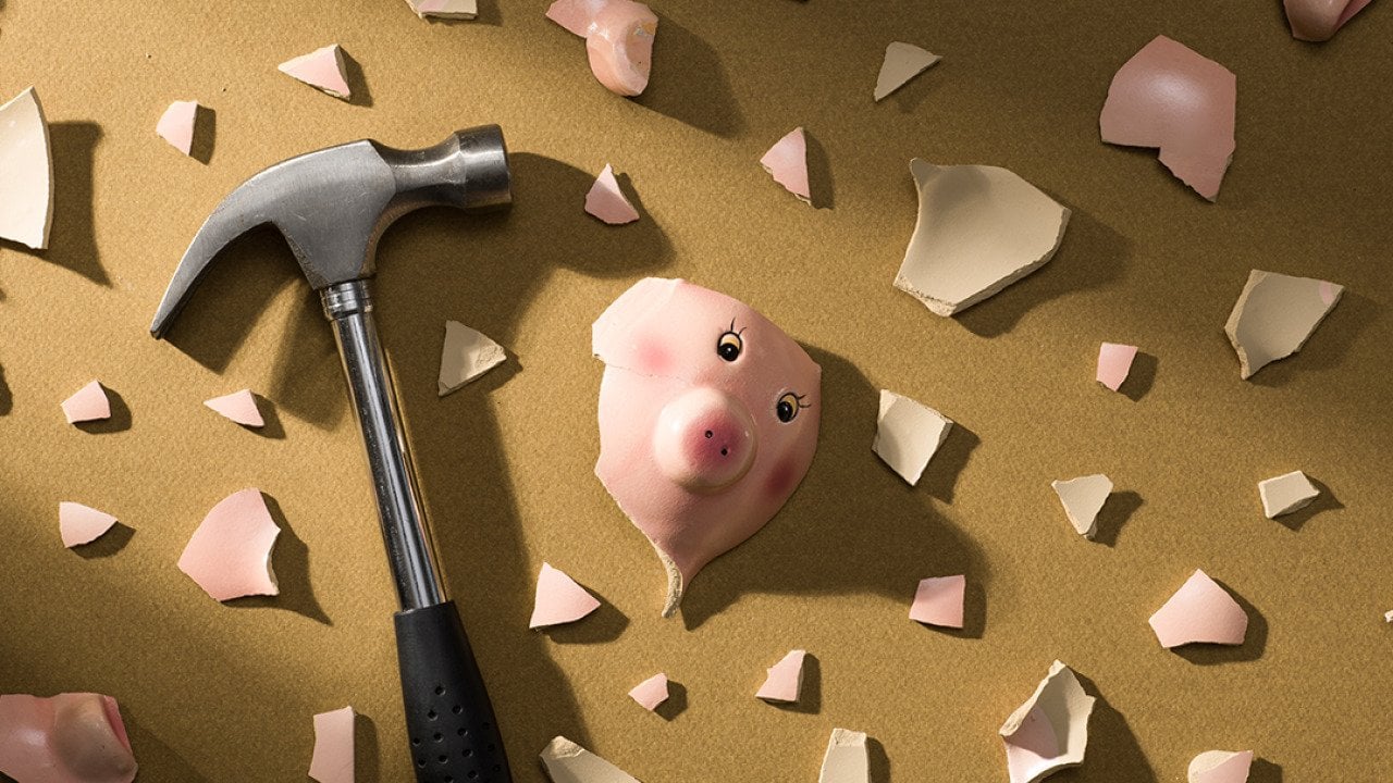 A broken piggy bank and a hammer on the floor.